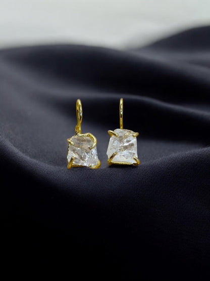 Clear Quartz gemstones studs on a dark fabric background